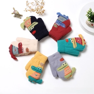 Flat lay of colorful knit toddler mittens with 3D crocodile patterns and elastic cuffs