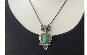 Detail view of owl pendant with green oval gemstone and vintage silver feather textures
