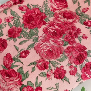 Close-up of vintage pink floral jacquard fabric with detailed red rose embroidery