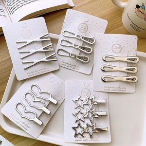 Close-up of silver Y2K metallic hair clips in geometric shapes on a wooden desk