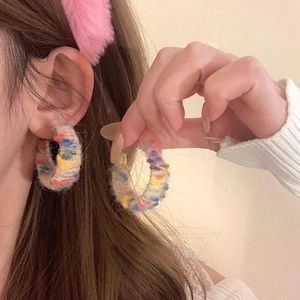Detail view of colorful knitted hoop earrings with handmade bohemian yarn texture