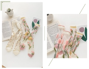 Detail of sheer glass socks with delicate pink tulip floral embroidery in white