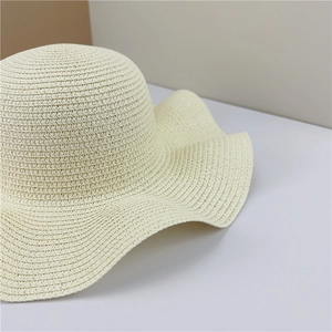 Close-up of creamy white straw sun hat showing dense weave and wavy brim details
