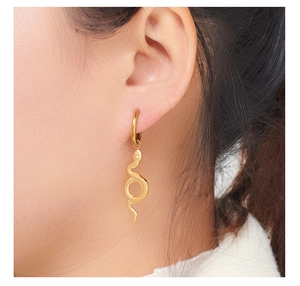 Close-up of golden snake pendant earring with detailed texture worn on a model's ear