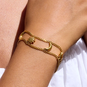 Close-up of double layer gold sun and moon star chain bracelet worn on wrist