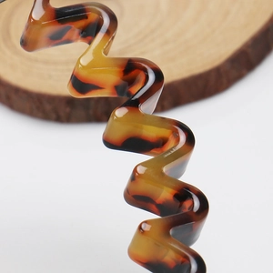 Detail view of wavy tortoise shell acetate headband with ergonomic non-slip grip design