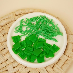 Trozos y tiras de pimiento verde artificial de PVC en un plato de cerámica blanca