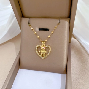 Close-up of golden heart pendant with crystal border and red-eyed bear inside the gift box