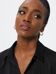 Detailed view of model wearing textured gold striped hoop earrings for women
