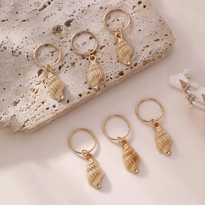 Set of six golden conch shell hair accessories for children's braids on a natural stone base