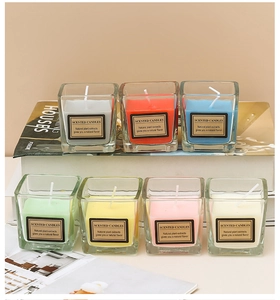 Detailed arrangement of seven candy-colored scented candles in square glass jars on a white surface