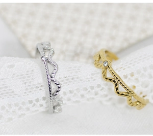 Detail of wavy gold and silver rings with zircon inlay on textured lace background