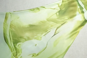 Gros plan sur la texture du tissu imprimé marbre vert et les coutures d'une robe licou
