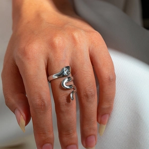 Macro shot of silver snake-shaped stainless steel wrap ring with polished metallic luster