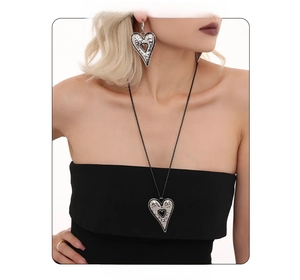Detail of silver hammered heart necklace and earrings with minimalist ring on model