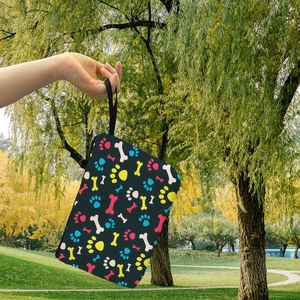 Portable makeup bag with colorful bone and paw prints held in an outdoor setting
