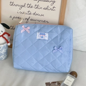 Detail of blue quilted cosmetic bag featuring soft fabric and decorative bow accents