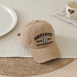 Macro detail of embroidered letter B and distressed brim on washed khaki cotton baseball cap