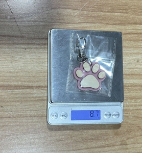 Detail shot of a pink and white wood paw pendant on a scale weighing 8.7g with metal clasp