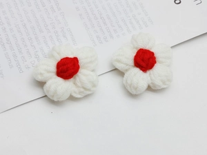 Detailed macro view of two handmade white and red crochet yarn flowers for DIY accessories