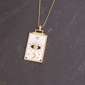 Macro detail of gold square pendant with evil eye moon and star motifs on stone surface