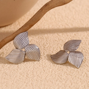 Macro shot of silver leaf earrings featuring brushed metal texture on embossed background