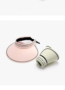 Detail of pink and beige sun visors with wide brims and black contrasting trim