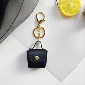 Macro view of black lychee grain leather mini bag keychain with golden snap button