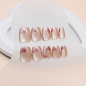 Short square champagne cat-eye press-on nails with red heart patterns on display