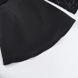 Detail eines eleganten schwarzen Kleides mit Spitzennaht und glatter Stoffstruktur