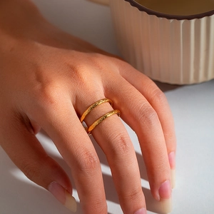 Detail of minimalist gold double-layered ring with hammered texture on a model's hand