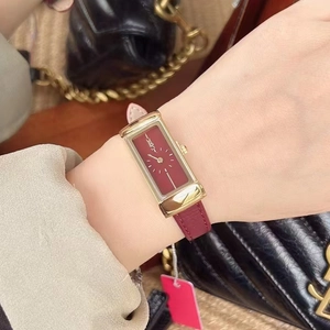 Close-up of elegant gold rectangular watch with red leather strap on female wrist