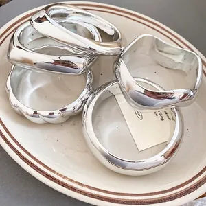 Set of minimalist geometric silver bracelets with polished mirror finish in a tray