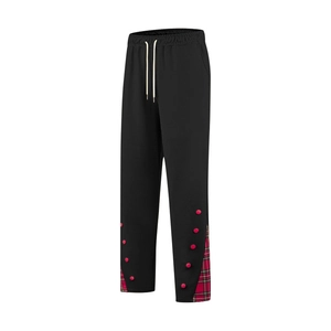 Détail de la taille élastique à cordon et patchwork à carreaux rouges sur pantalon noir