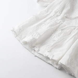 Macro shot of 3D floral embroidery and fine textured fabric on white summer set