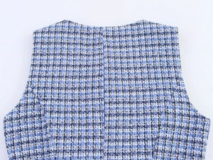 Détail de la texture du tissu en tweed bleu et blanc tissé sur le dos du gilet pour femme