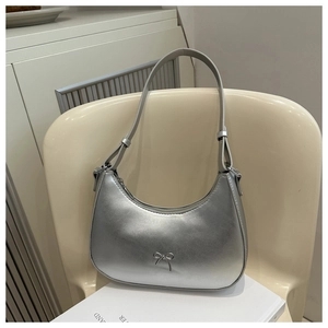 Detailed view of a silver metallic shoulder bag featuring a stylish bow and adjustable strap