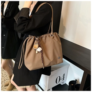 Detail of tan nylon tote bag with drawstring closure and baseball glove charm