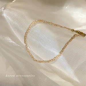 Detail of beige crystal beaded anklet on white silk fabric with elegant Korean style