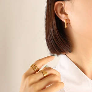 Minimalist gold-plated titanium earrings and geometric rings set on female model