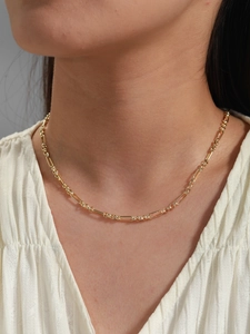 Detail of minimalist gold chain necklace with polished oval and round link patterns