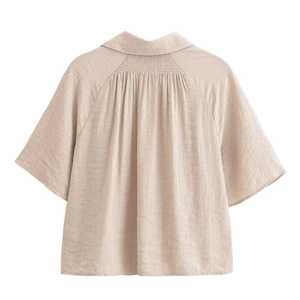 Detail of beige cotton linen blend short jacket showing back pleats and fabric texture