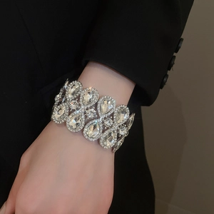 Close-up of wide silver stretch bracelet with teardrop crystals on a black suit sleeve