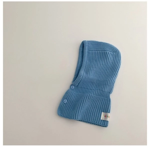 Detail of blue knitted balaclava with soft texture and side decorative buttons