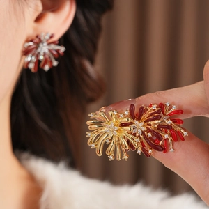 Vue macro des boucles d'oreilles fleur dorées avec émail rouge et pierres de zircon