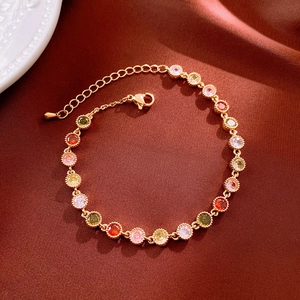 Gros plan d'un bracelet plaqué or avec zircons colorés sur fond de soie rouge