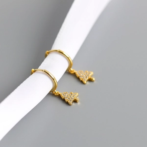 Detailed close-up of golden Christmas tree hoop earrings with pavé zircons on silk