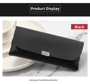 Close-up of a black leather texture eyeglass case with a silver metal buckle on marble