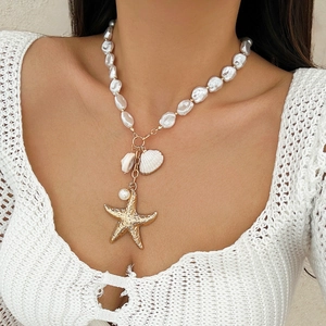 Detail shot of a starfish pendant and shell charm on an irregular pearl necklace