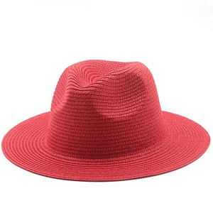 Detail of red wide brim straw hat showing fine spiral woven texture and vibrant color
